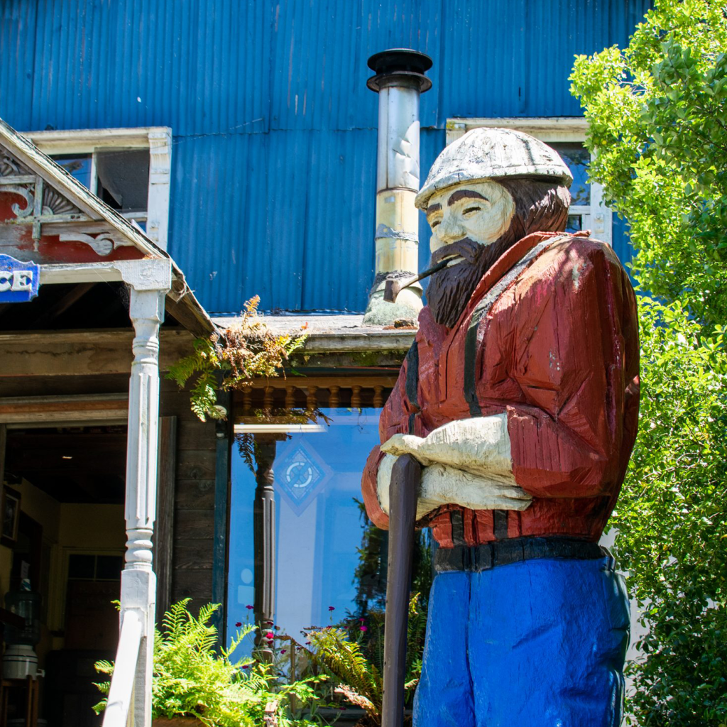 Wooden statue of a man outside a blue building
