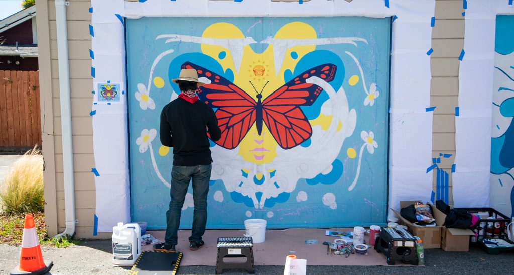 man painting a mural on a garage door