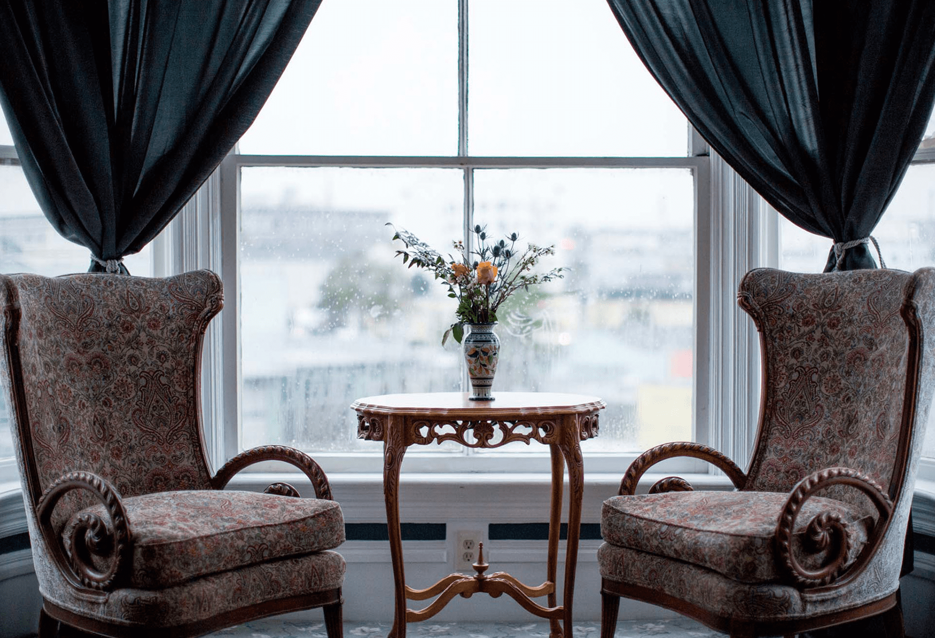 two chairs and flowers in a vase by a window
