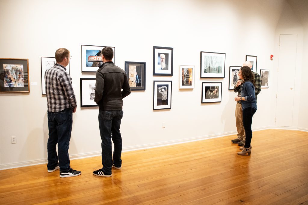 People looking at photographs on the walls in a gallery