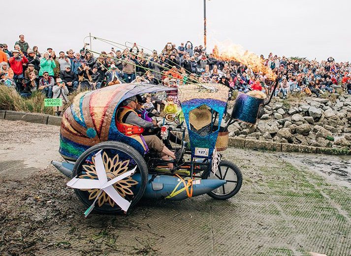 A brightly colored kinetic machine driving towards water